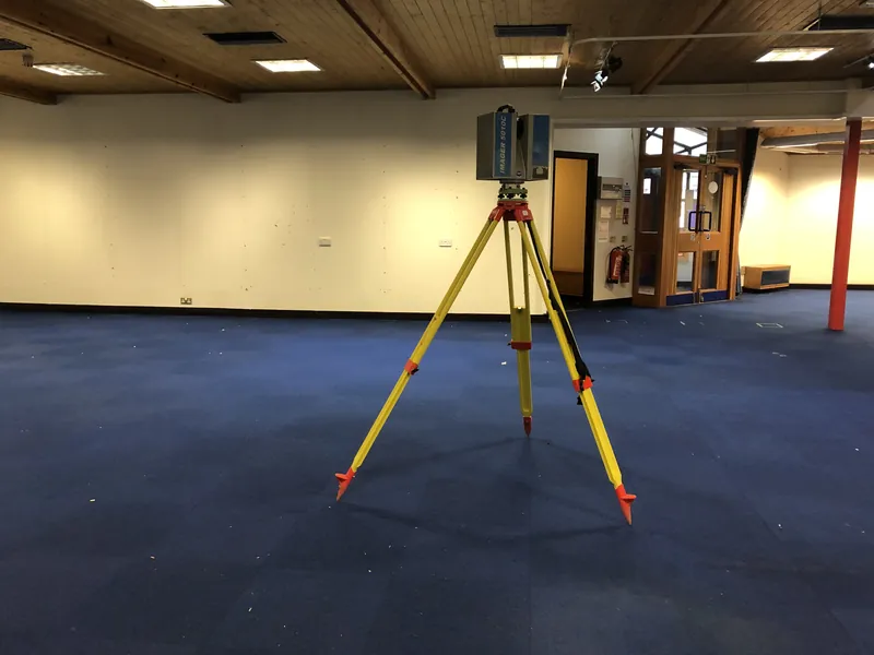A laser scanner on a tripod in an empty office floor